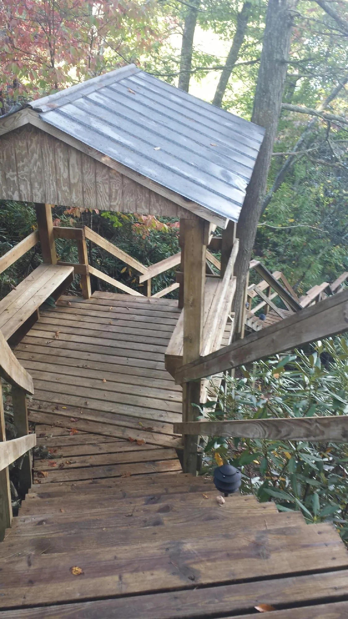 Metal roofed shelter over wooden steps on a wooded walkway — Skylight Repair & Installation work by our crew in Andover
